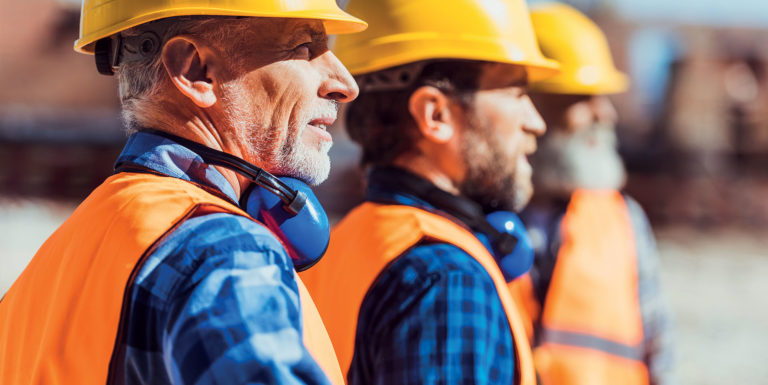 Trois hommes sur un chantier portant un casque de sécurité - arrêt de travail et reprise d'une activité