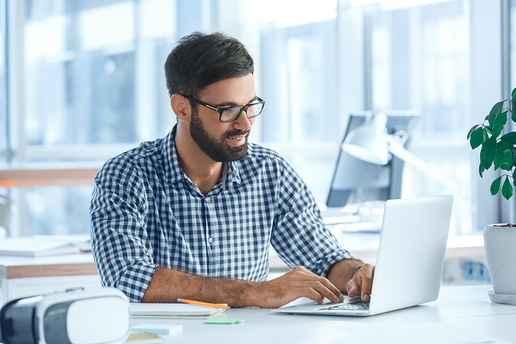 Un homme au bureau sur son ordinateur étudiant des DSN Un homme au bureau sur son ordinateur étudiant des DSN