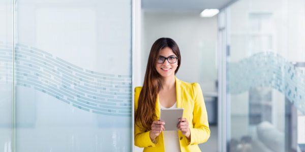 Jeune femme avec une veste jaune tenant un livre au bureau - Easyprojet