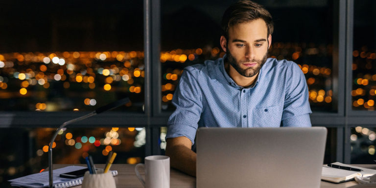 Un homme à son bureau la nuit regardant son portail Ma Protection Sociale (MAPSO) sur son ordinateur