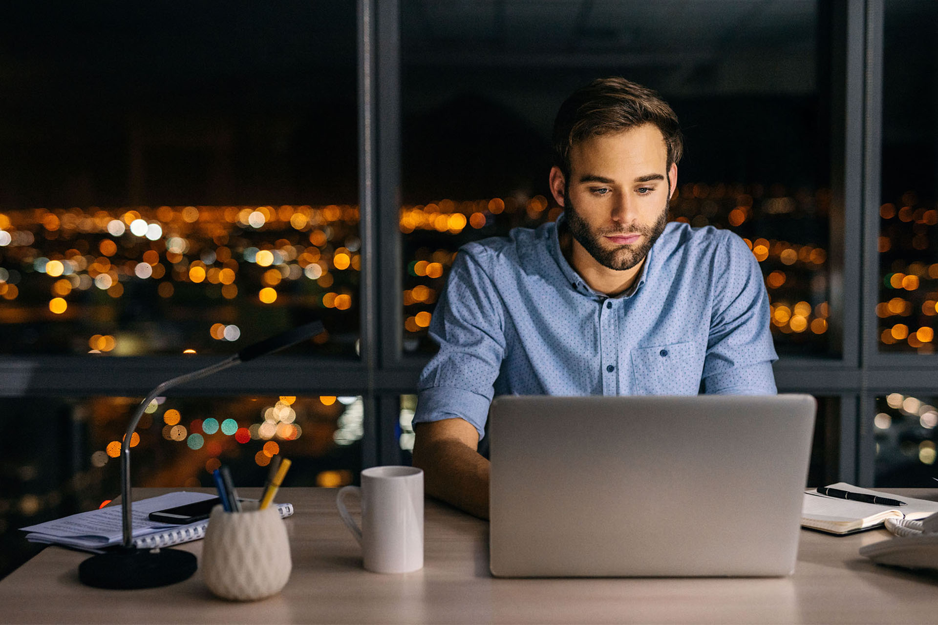 Un homme à son bureau la nuit regardant son portail Ma Protection Sociale (MAPSO) sur son ordinateur