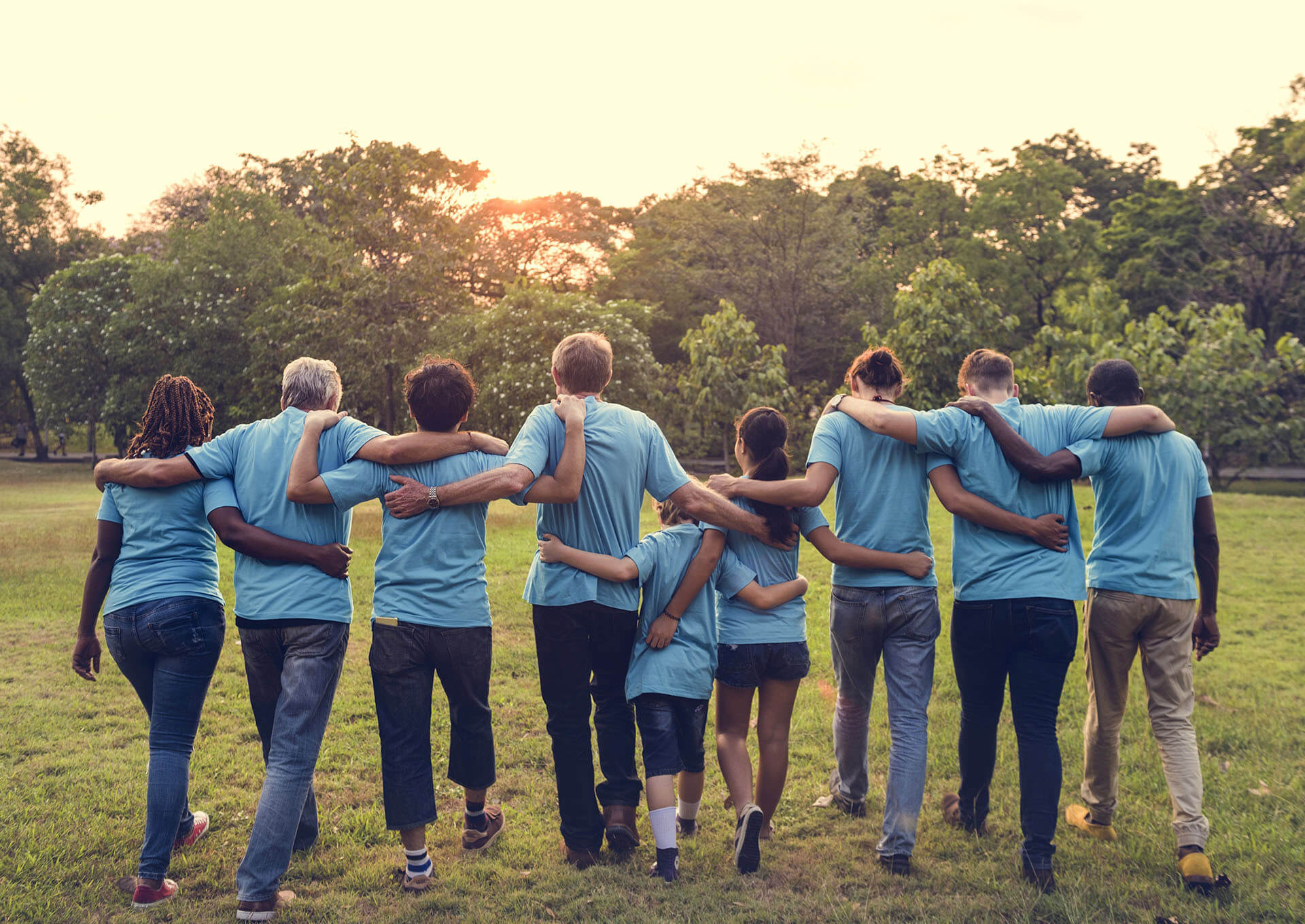 Des hommes et des femmes ayant le même tee-shirt bleu se tenant par les épaules et marchant ensemble