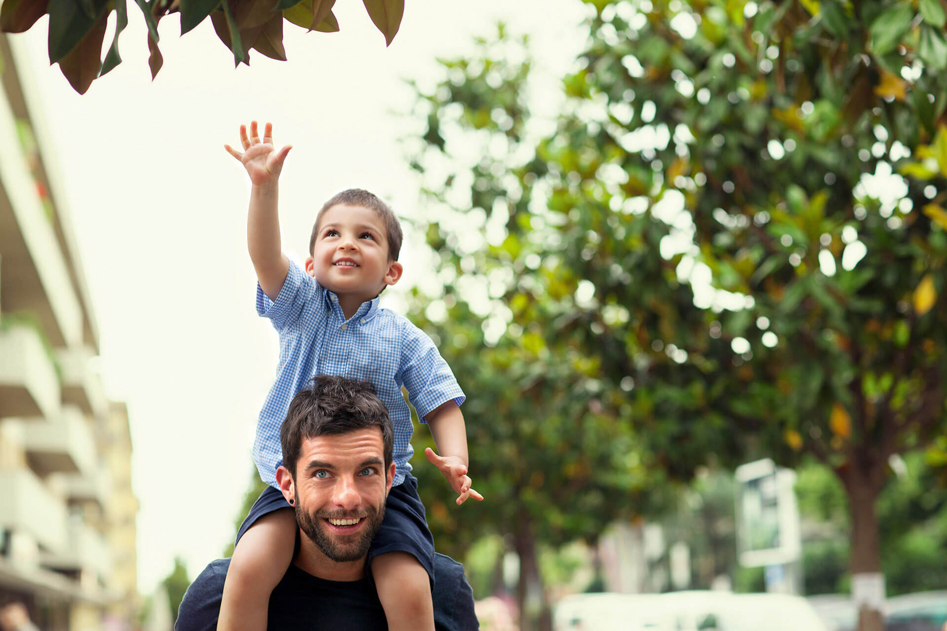 Un homme souriant portant son fils sur les épaules dans la rue Un homme souriant portant son fils sur les épaules dans la rue