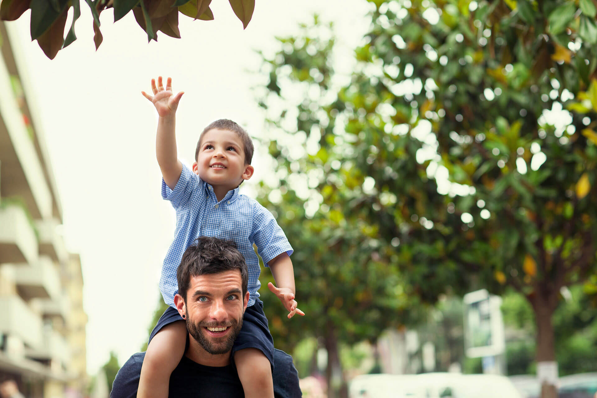 Un homme souriant portant son fils sur les épaules dans la rue