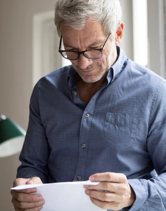 Un homme portant des lunettes et lisant un papier - financer ses projets pour une retraite occupée