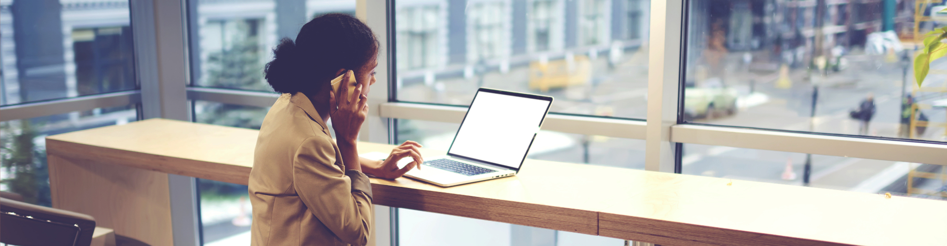 Une femme au bureau au téléphone devant son ordinateur