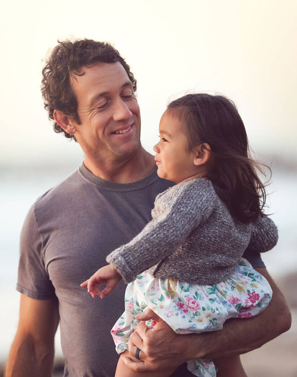 Un homme tenant sa fille dans les bras sur une plage