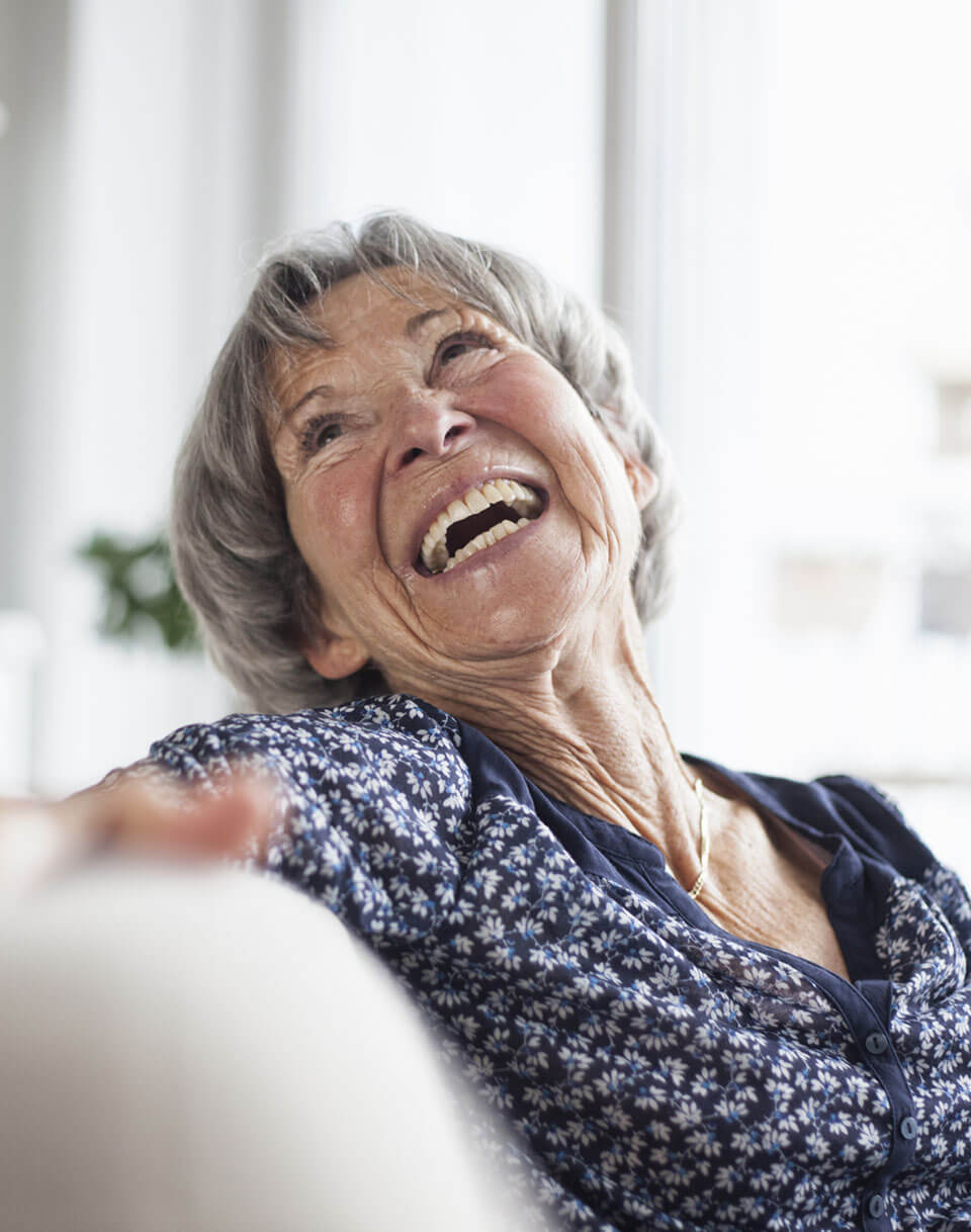 Femme senior assise et rigolant sur un canapé