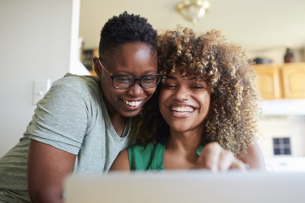 Deux femmes souriantes regardant sur leur ordinateur leurs contrats santé adaptés à la réforme 100% santé