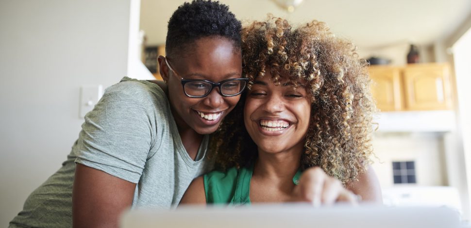 Deux femmes souriantes regardant sur leur ordinateur leurs contrats santé adaptés à la réforme 100% santé