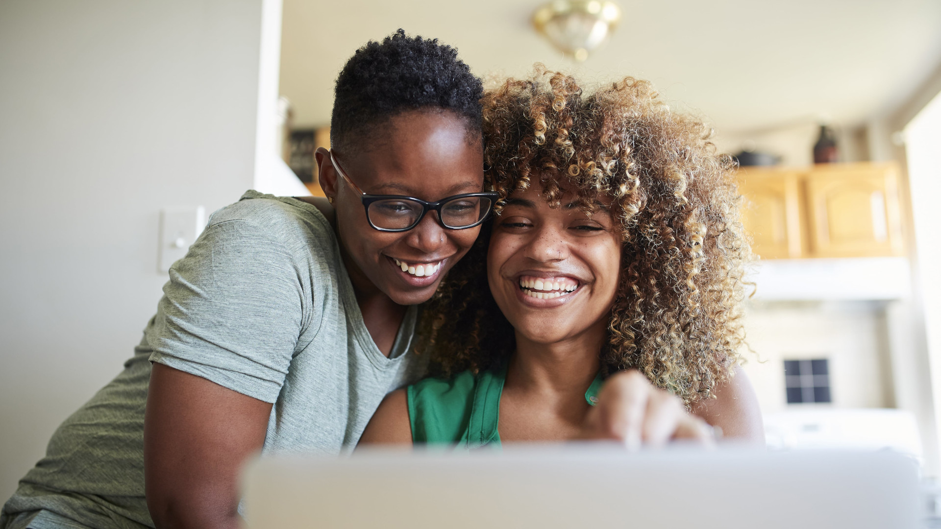 Deux femmes souriantes regardant sur leur ordinateur leurs contrats santé adaptés à la réforme 100% santé