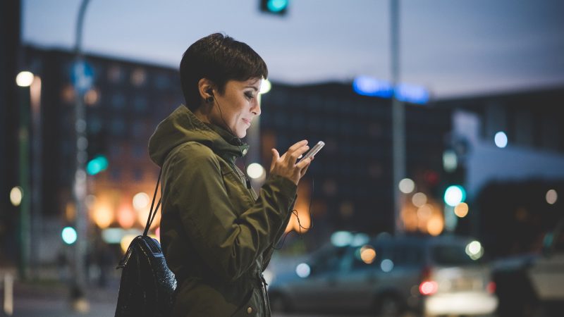 Une femme expatriée dans la rue sur son téléphone