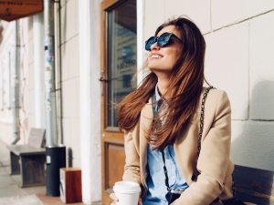 Une femme assise dehors avec un café - complémentaire santé