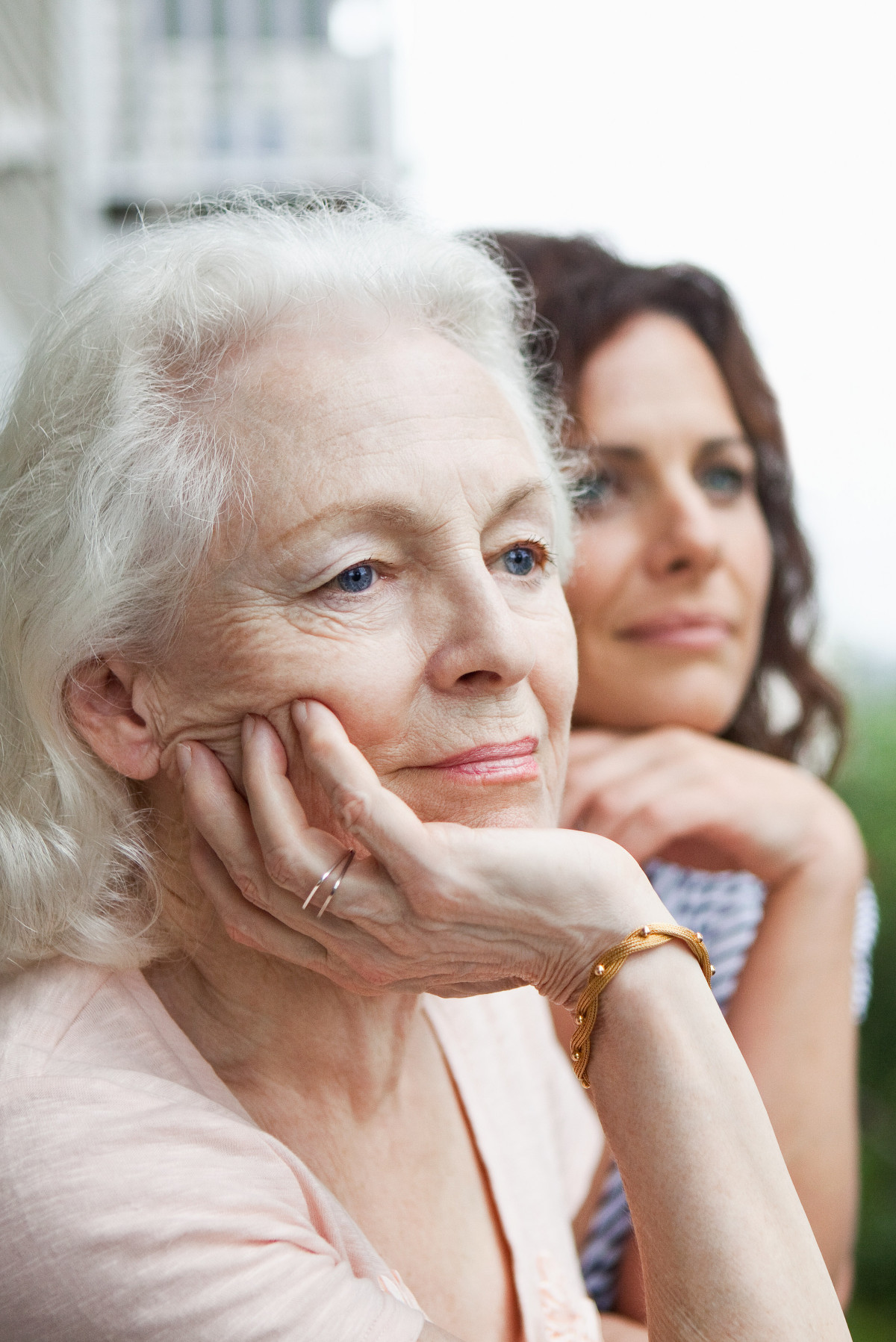 Une mère senior pensive regardant au loin avec sa fille à ses côtés - grand âge et autonomie Une mère senior pensive regardant au loin avec sa fille à ses côtés - grand âge et autonomie