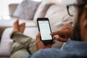 Un homme dans son canapé consultant sur son téléphone les obligations pour l'employeur