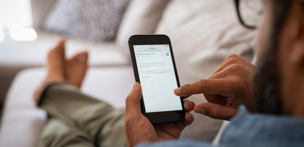 Un homme dans son canapé consultant sur son téléphone les obligations pour l'employeur