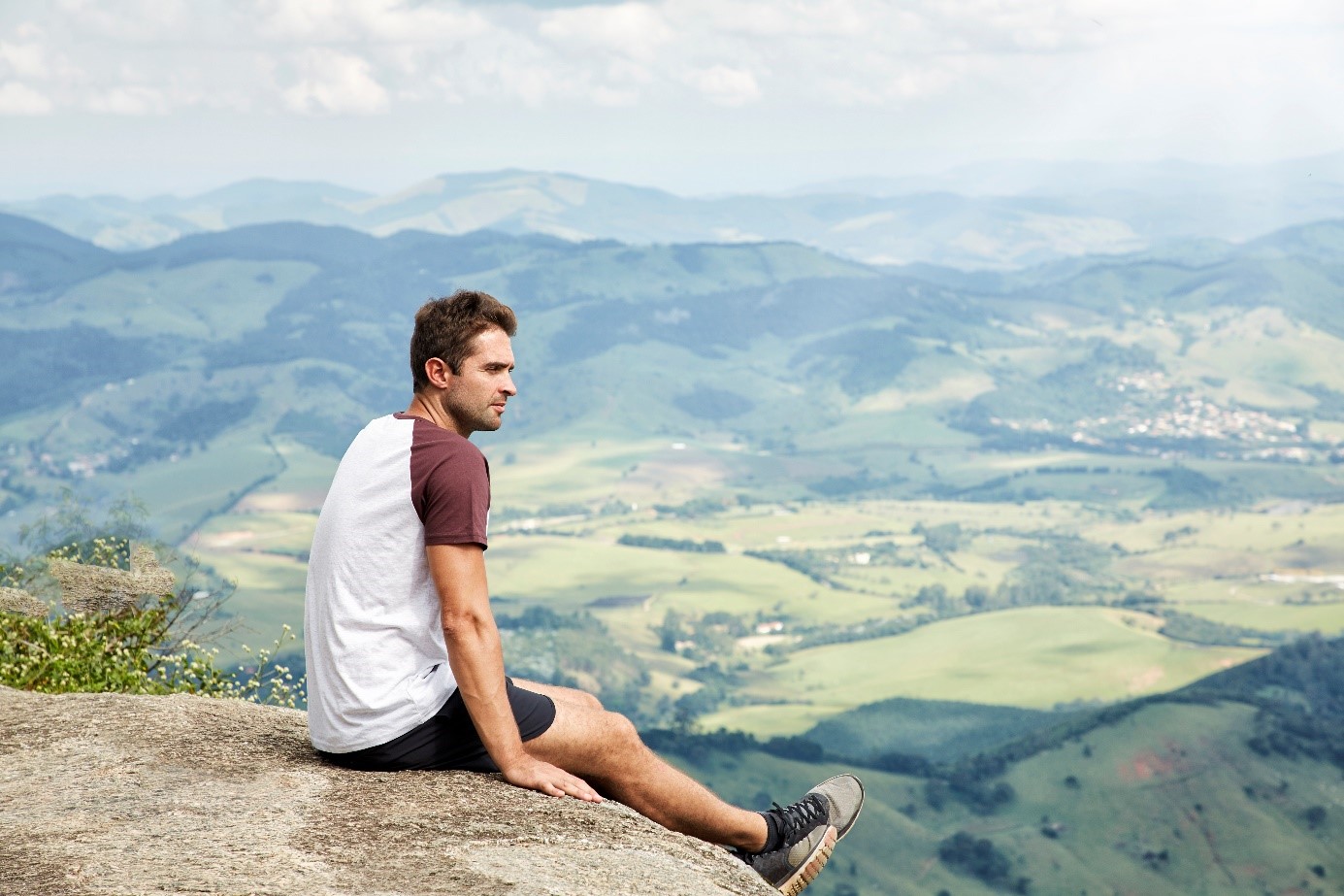 Un homme assis au bord d'une falaise et regardant au loin - violences conjugales