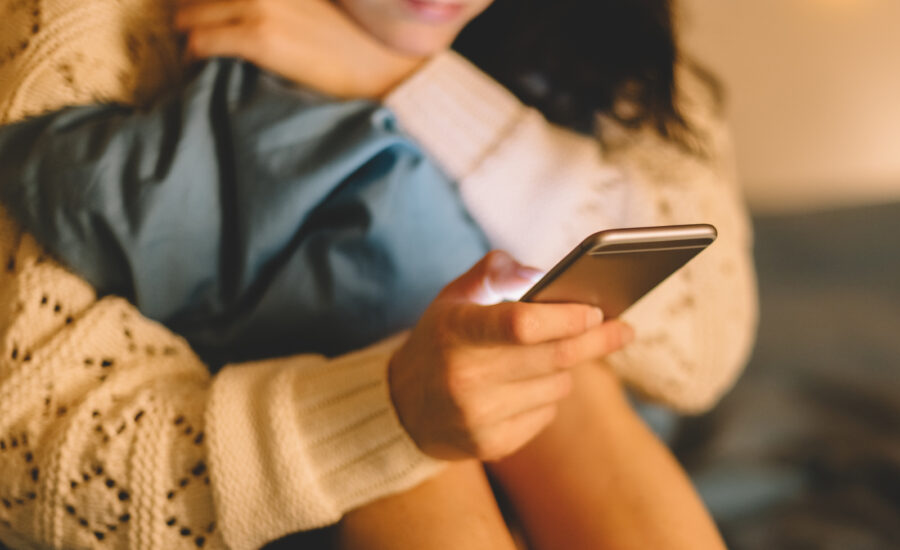 Une femme victime de violences conjugales recroqueviller sur elle et utilisant son téléphone Une femme victime de violences conjugales recroqueviller sur elle et utilisant son téléphone
