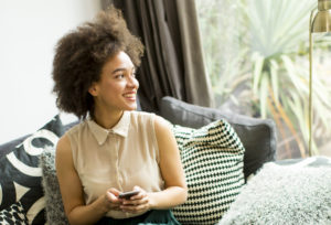 Une apprentie regardant ses droits en matière de protection sociale sur son téléphone et souriant