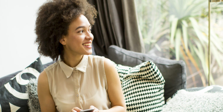 Une apprentie regardant ses droits en matière de protection sociale sur son téléphone et souriant