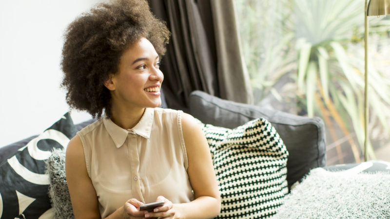 Une apprentie regardant ses droits en matière de protection sociale sur son téléphone et souriant