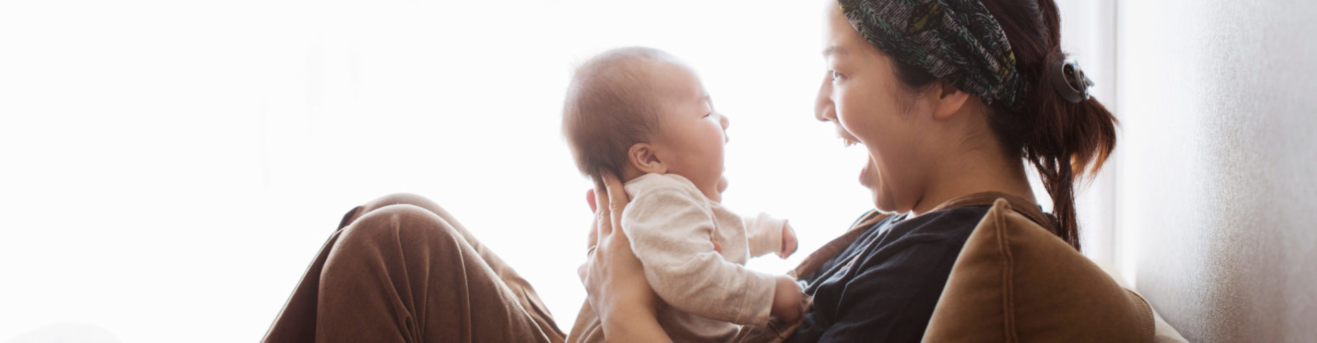 Une mère en congé maternité jouant et rigolant avec son bébé dans les bras