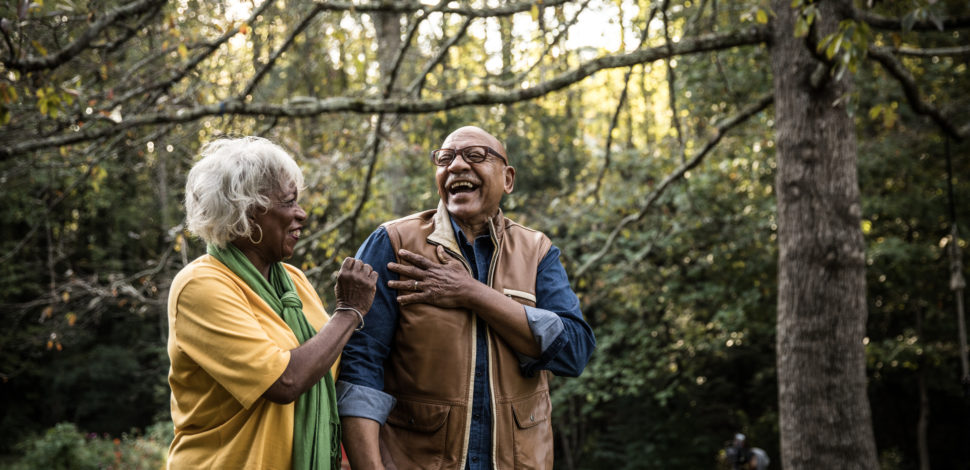 Un homme et une femme sénior rigolant ensemble dans le jardin