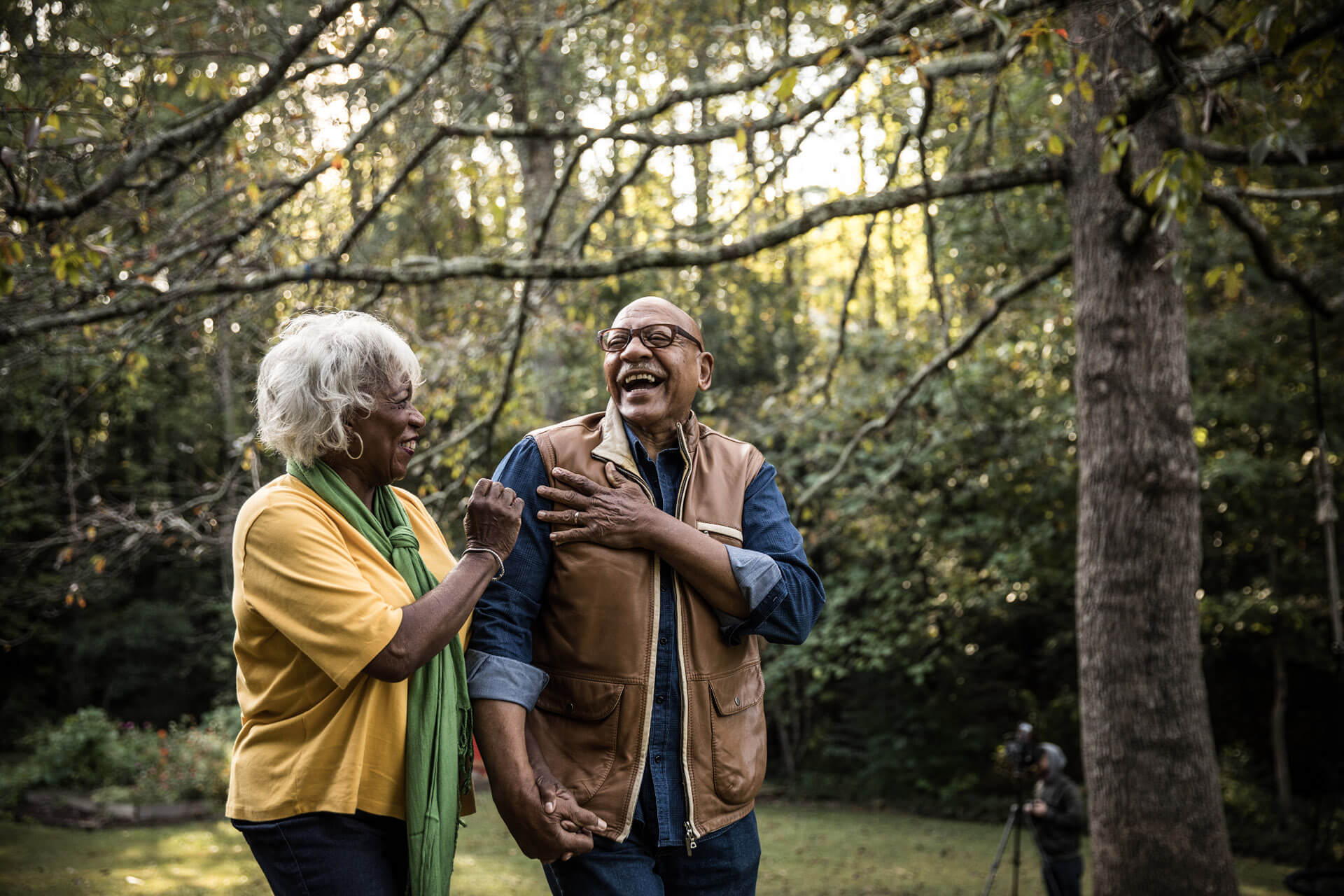 Un homme à moustache et une femme sénior rigolant ensemble dans le jardin