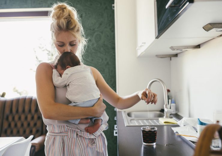 Une mère en congé maternité se préparant un café avec son bébé dans les bras