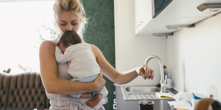 Une mère en congé maternité se préparant un café avec son bébé dans les bras