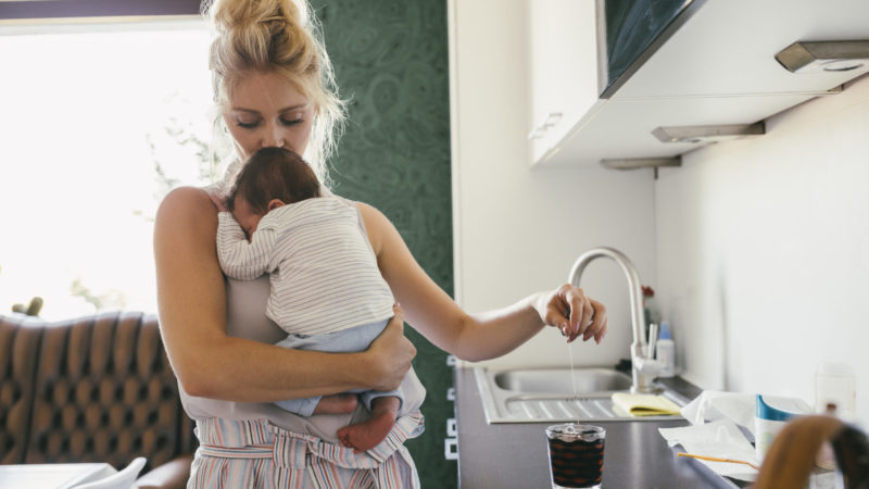 Une mère en congé maternité se préparant un café avec son bébé dans les bras