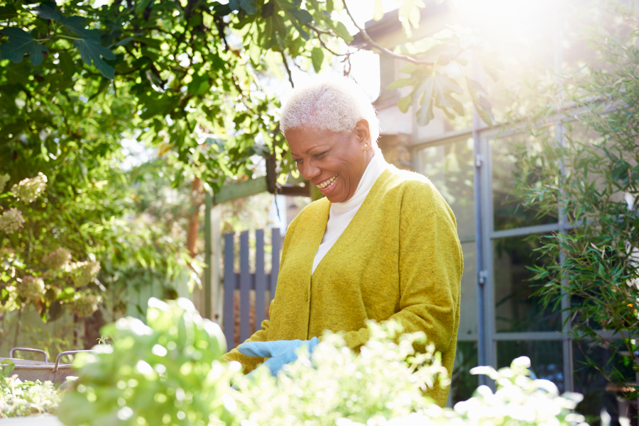Une femme souriante s'occupant de son jardin sous le soleil - épargne salariale