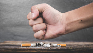 Un poing fermé écrasant une cigarette pour le mois sans tabac - cancer