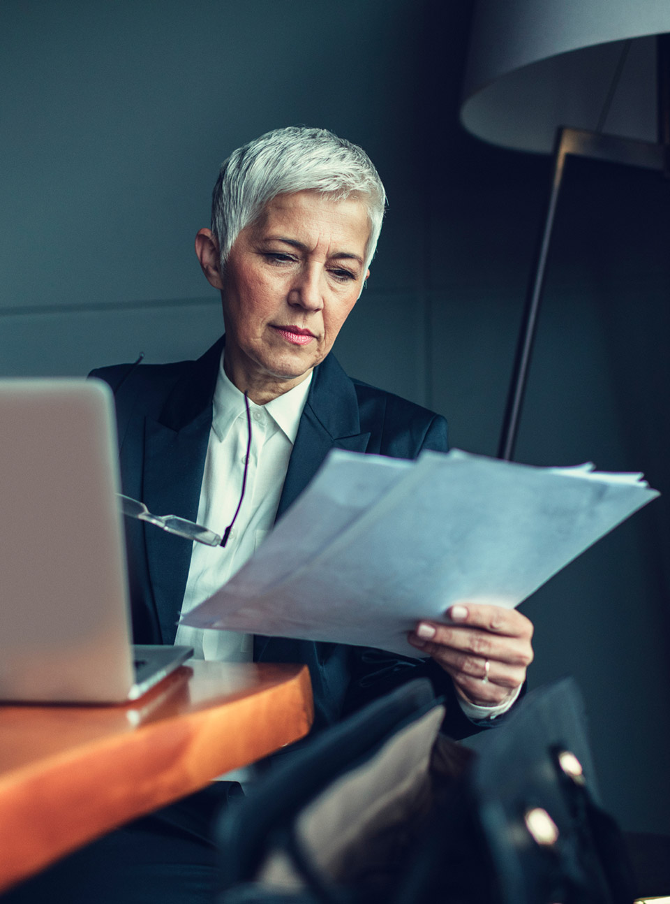 Une femme lisant des documents papiers à son bureau - Avantages nouveau PER entreprise