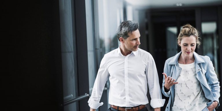 un homme et une femme marchant et discutant en entreprise - TPE et PME Loi Pacte