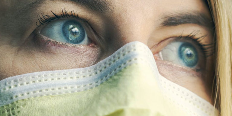 Une femme aux yeux bleus portant un masque - faire face à la maladie