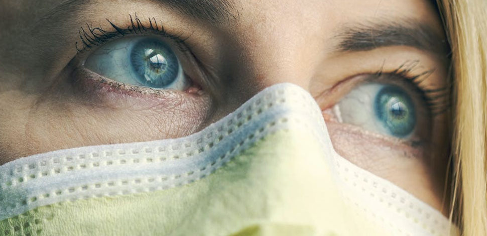 Une femme aux yeux bleus portant un masque - faire face à la maladie