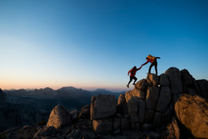 Deux personnes s'aidant à gravir une montagne