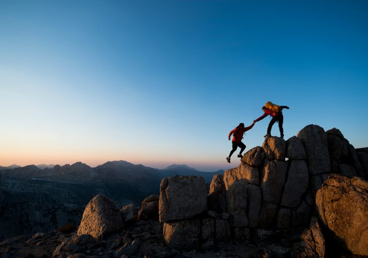 Deux personnes s'aidant à gravir une montagne
