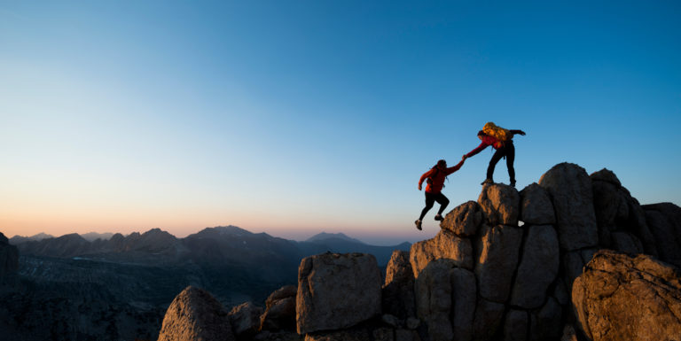 Deux personnes s'aidant à gravir une montagne