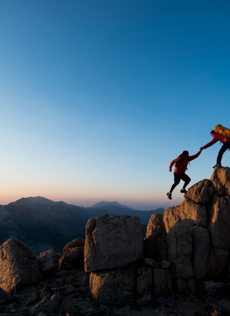 Deux personnes s'aidant à gravir une montagne