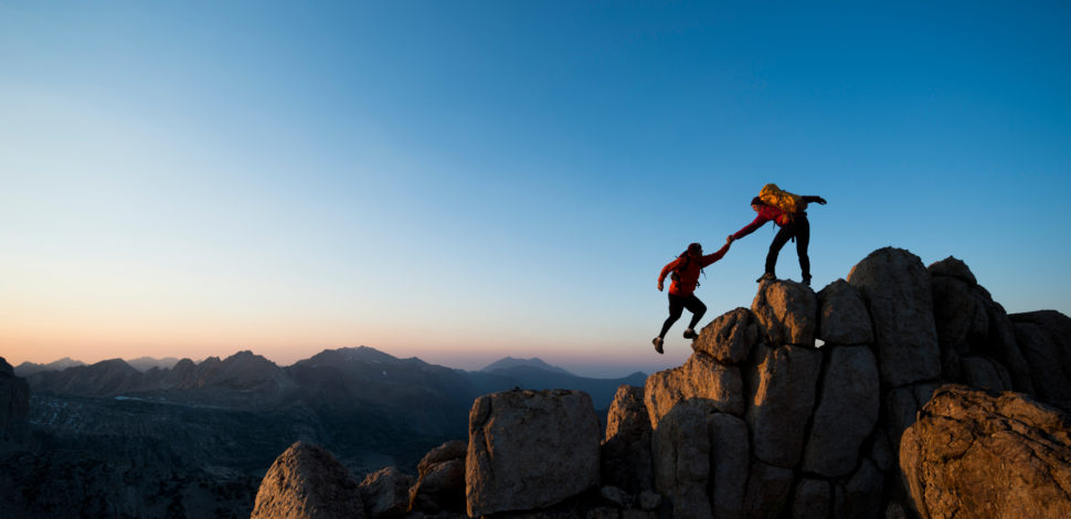 Deux personnes s'aidant à gravir une montagne