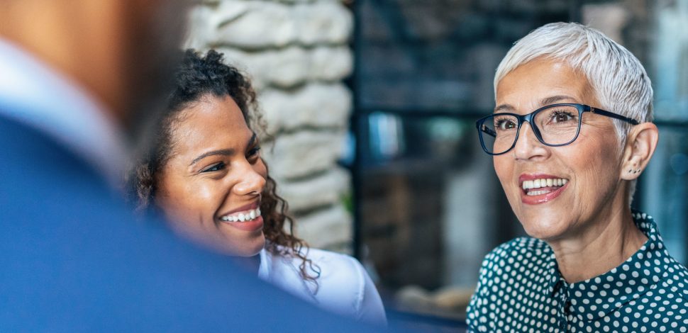 Une femme souriante en discussion avec des collègues en entreprise - régimes article 39