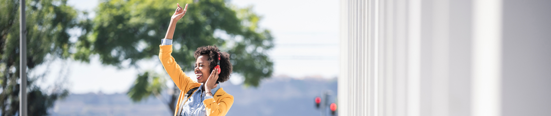 Une jeune stagiaire heureuse dans la rue et écoutant de la musique - protection sociale