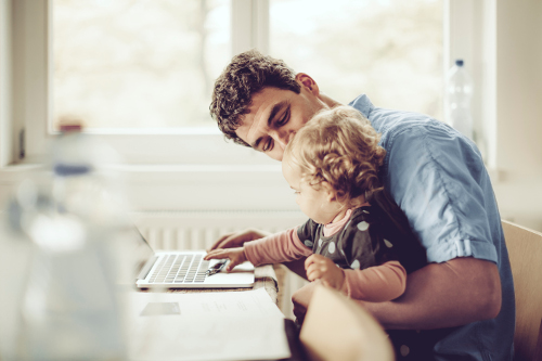 Un homme avec son enfant sur les genoux s'informant sur la fiche désignation bénéficiaire sur son ordinateur