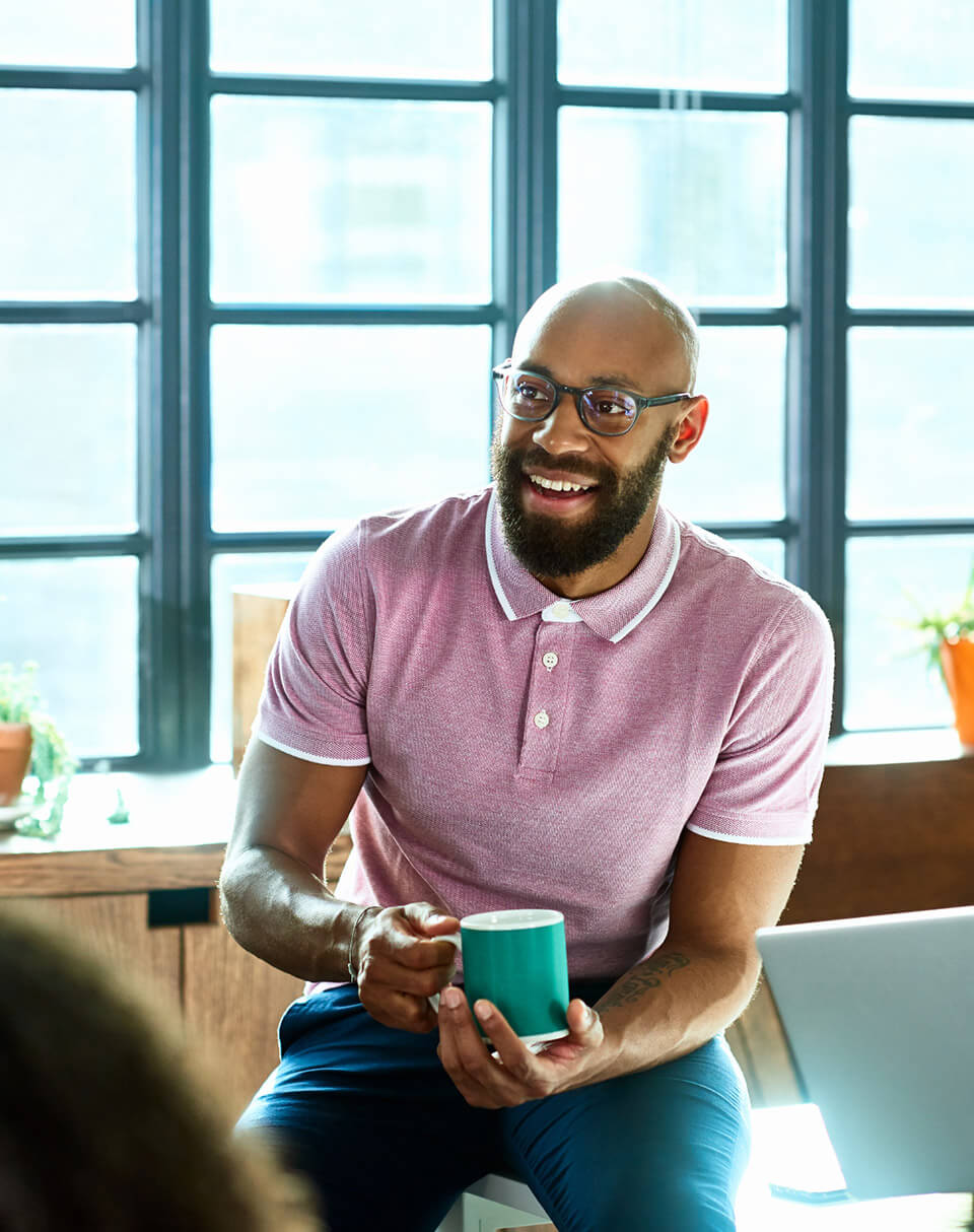 Un homme discutant et tenant sa tasse à la main - qualité de vie au travail