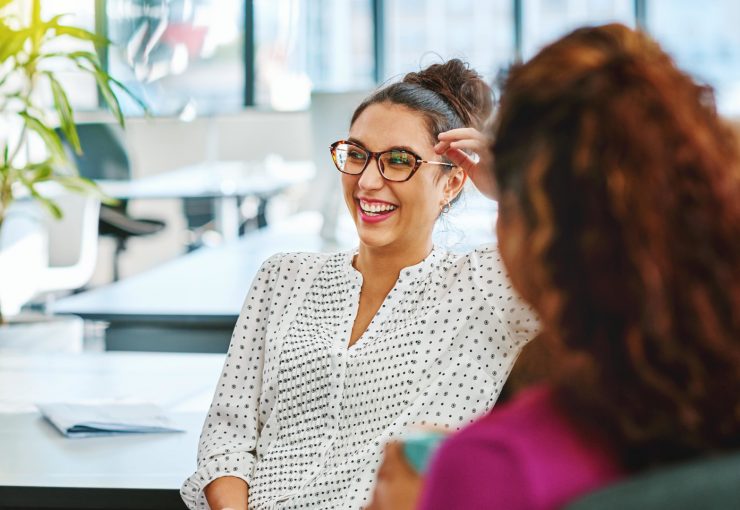 Une femme portant des lunettes discutant et rigolant lors d'une conversation au travail - qualité de vie au travail