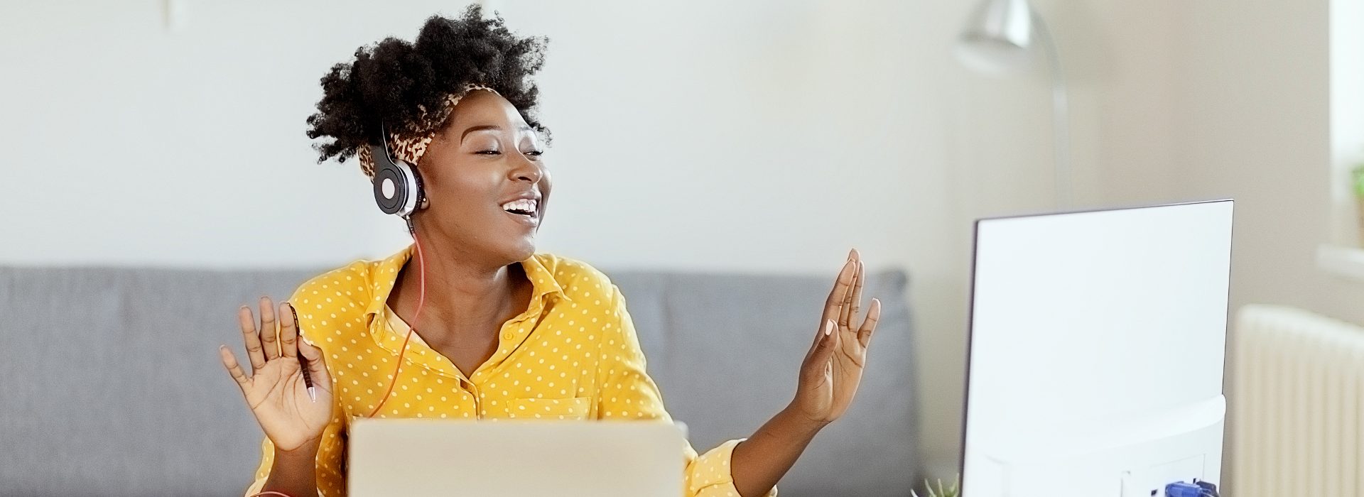 Une femme souriante devant son ordinateur et un casque écoutant la playlist Youtube ERE