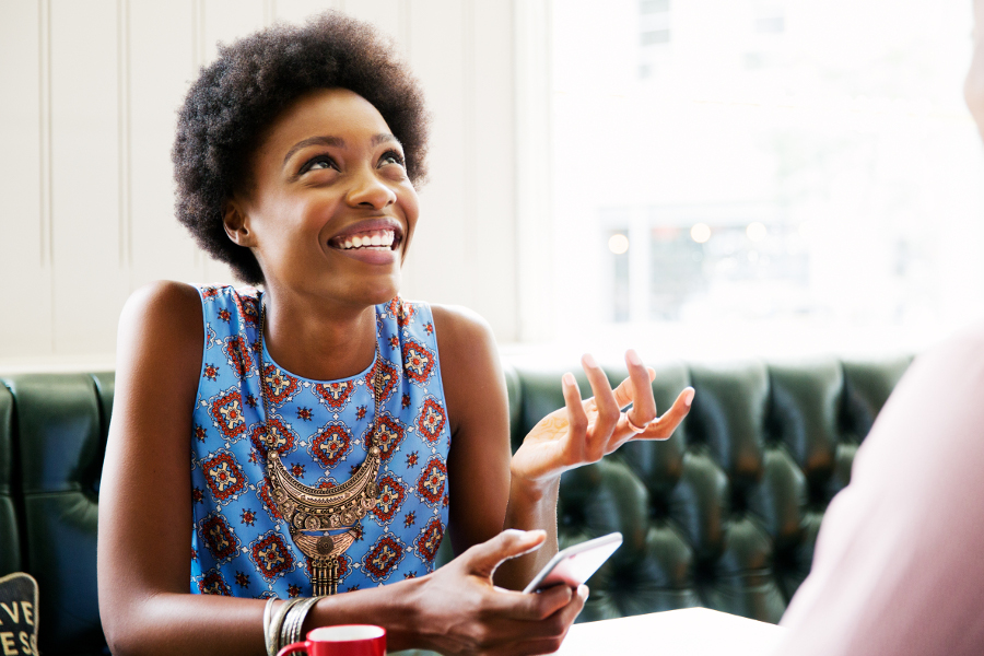 Une femme souriante utilisant son téléphone et discutant avec un ami des indicateurs ESG