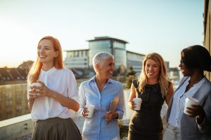 Groupe de femmes d'affaires sur le toit, tenant des gobelets en carton et riant - PER Unique